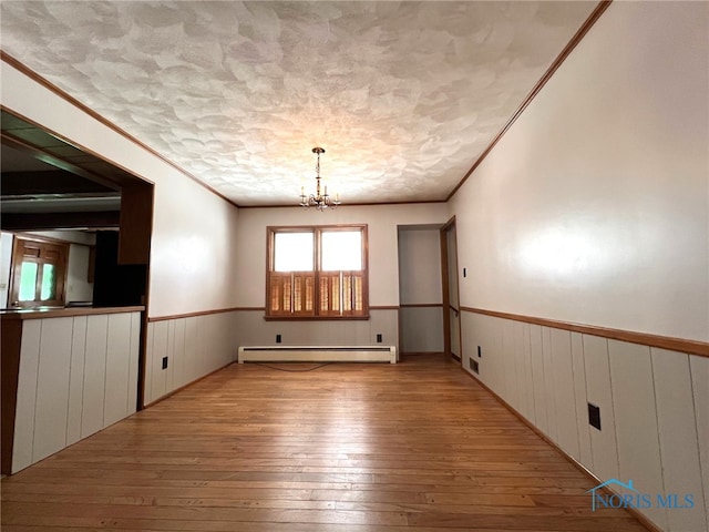 unfurnished room with an inviting chandelier, light hardwood / wood-style floors, a textured ceiling, and baseboard heating