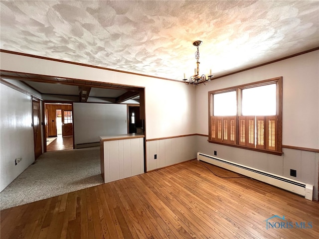 empty room featuring crown molding, wood-type flooring, a chandelier, and a baseboard heating unit