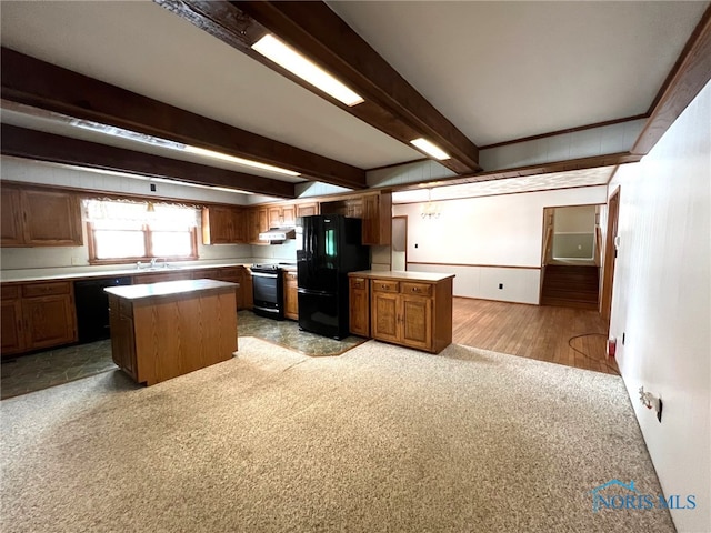 kitchen with sink, beam ceiling, black appliances, a kitchen island, and light carpet