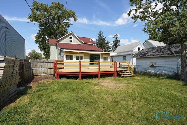 back of property with a deck and a yard