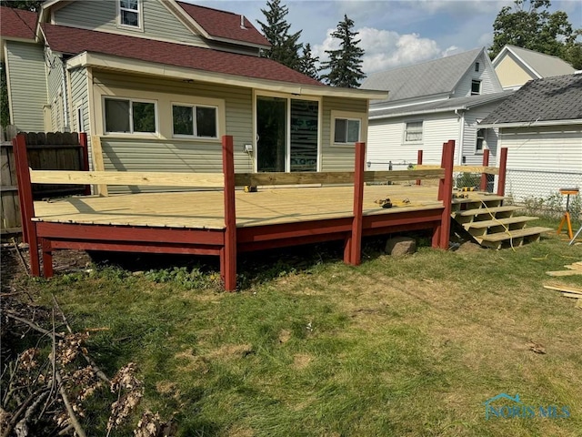 rear view of house featuring a deck and a lawn