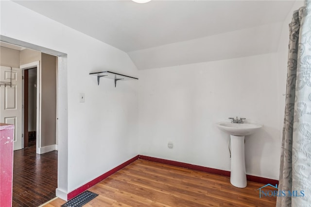 bathroom with wood-type flooring and vaulted ceiling