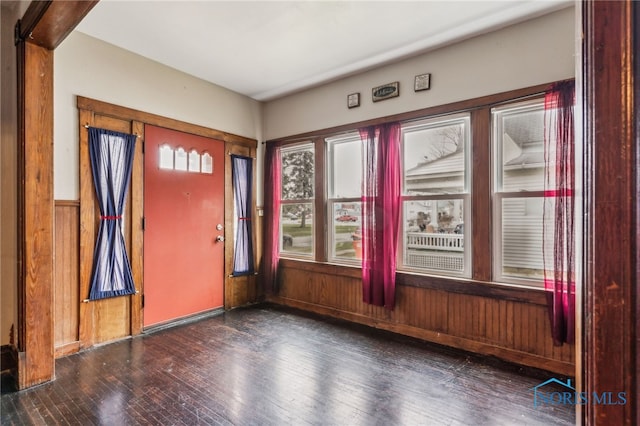 entrance foyer featuring dark hardwood / wood-style flooring and wooden walls