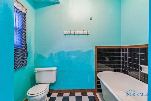 bathroom featuring a bathtub, tile walls, and toilet