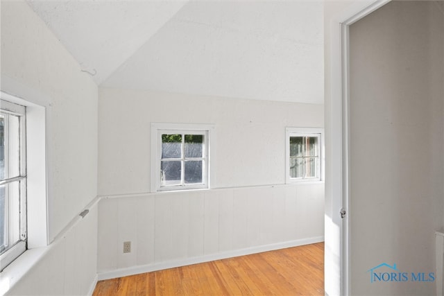 unfurnished room featuring light hardwood / wood-style floors and vaulted ceiling