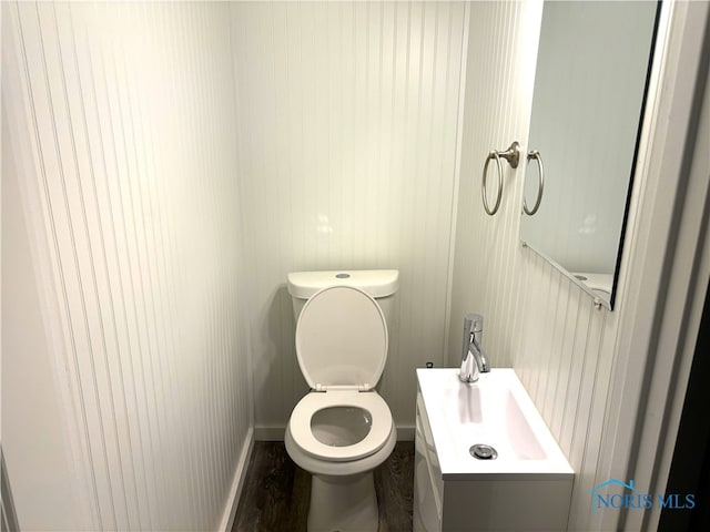 bathroom with hardwood / wood-style flooring, toilet, and vanity