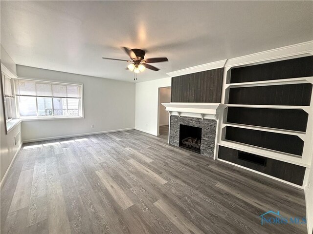 unfurnished living room with ceiling fan, hardwood / wood-style flooring, and a stone fireplace