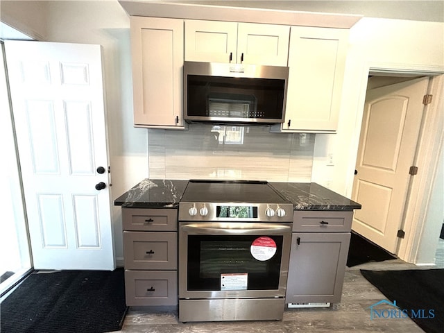 kitchen featuring dark stone counters, tasteful backsplash, appliances with stainless steel finishes, and gray cabinets