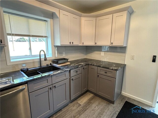 kitchen with tasteful backsplash, hardwood / wood-style floors, gray cabinetry, dishwasher, and sink