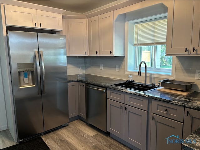 kitchen featuring light hardwood / wood-style flooring, tasteful backsplash, white cabinetry, sink, and stainless steel appliances