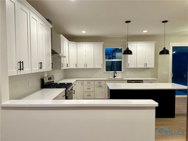 kitchen featuring gas range, white cabinetry, and decorative light fixtures