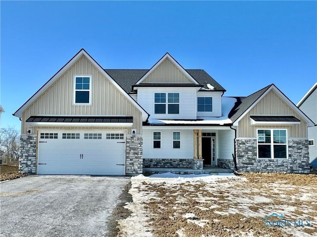 craftsman house featuring aphalt driveway, a standing seam roof, metal roof, and stone siding