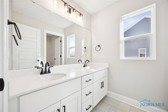 bathroom featuring double vanity, baseboards, and a sink