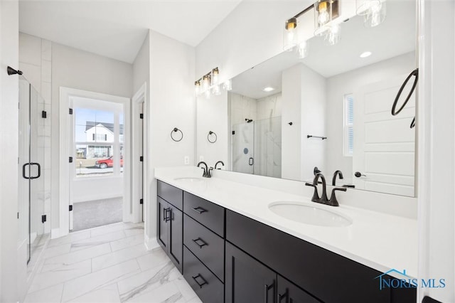 bathroom with double vanity, marble finish floor, a shower stall, and a sink