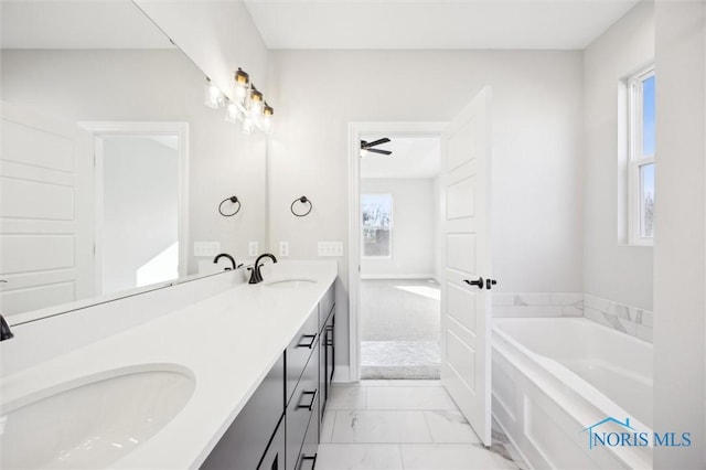 bathroom with double vanity, a healthy amount of sunlight, marble finish floor, and a sink