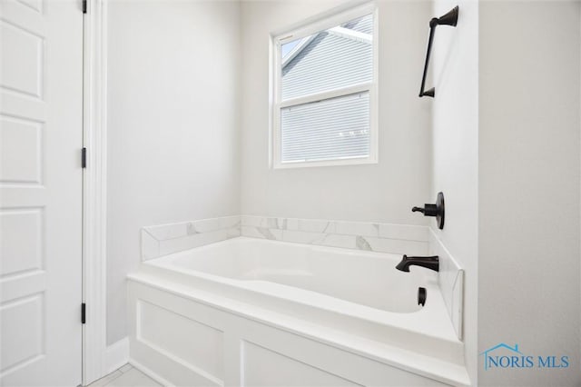 bathroom with marble finish floor and a bath