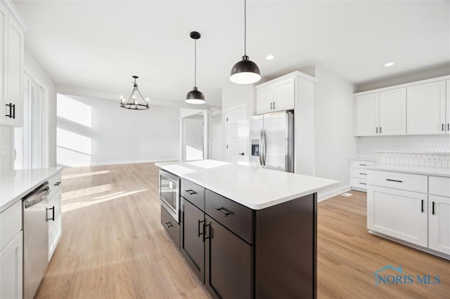 kitchen featuring tasteful backsplash, light wood finished floors, white cabinetry, and stainless steel appliances