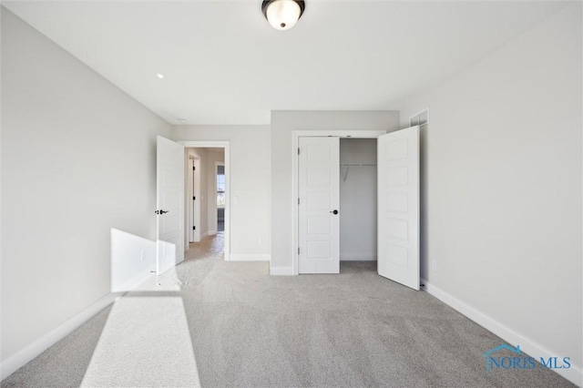 unfurnished bedroom featuring baseboards, light carpet, and a closet