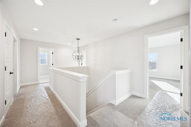 hallway with baseboards, an upstairs landing, light carpet, recessed lighting, and an inviting chandelier