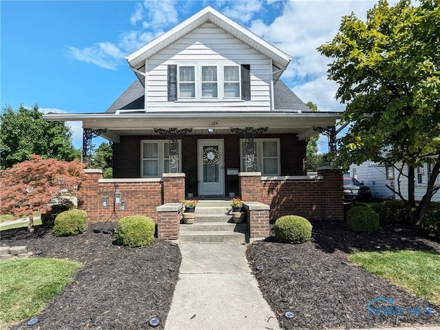 view of front of property featuring a porch, brick siding, and a shingled roof