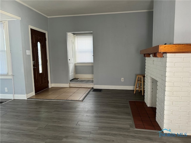 entryway with plenty of natural light, a fireplace, ornamental molding, and dark hardwood / wood-style flooring