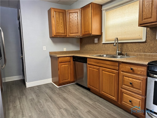 kitchen with appliances with stainless steel finishes, sink, and wood-type flooring