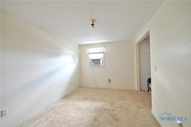 carpeted empty room featuring a textured ceiling and cooling unit