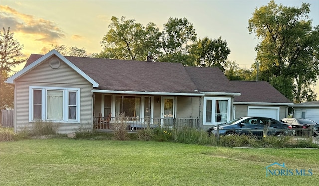 single story home with a garage, a yard, and covered porch