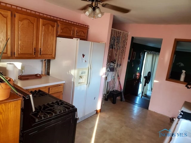 kitchen featuring ceiling fan, gas stove, and white refrigerator with ice dispenser