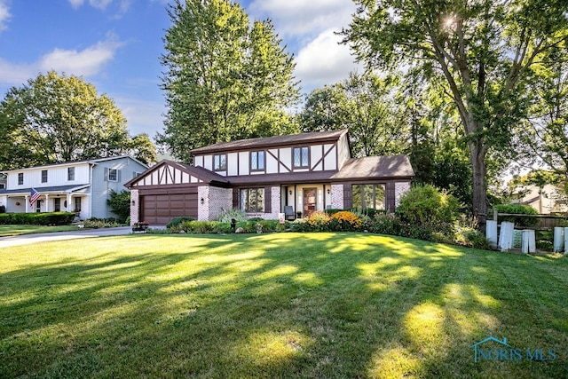 english style home featuring a garage and a front lawn