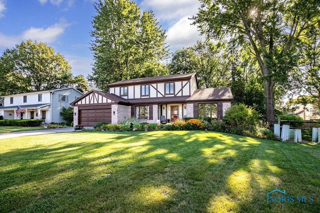 english style home featuring a garage and a front lawn