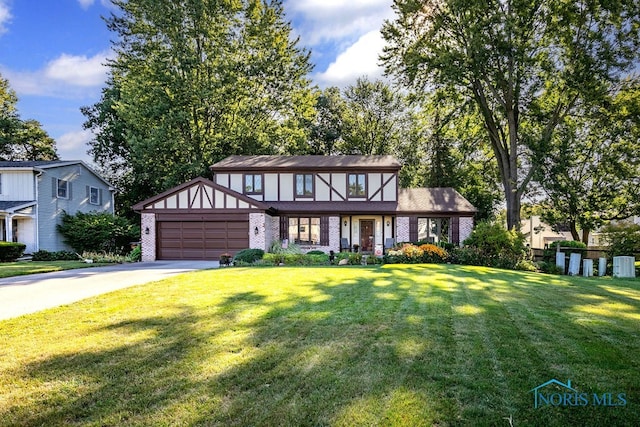 tudor home featuring a porch, a front yard, and a garage