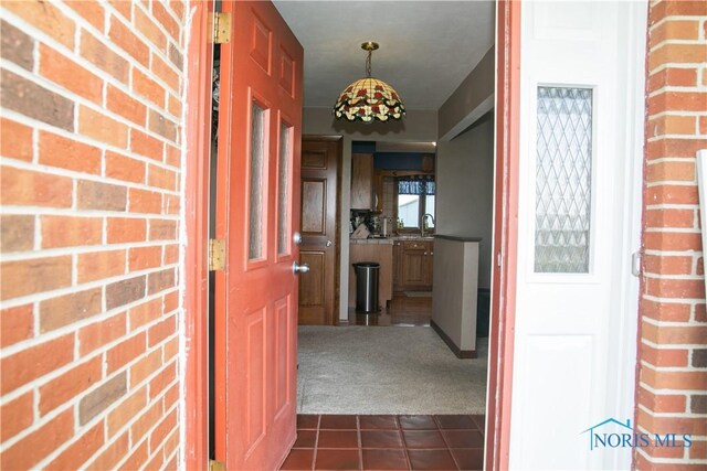 hall with dark carpet and brick wall