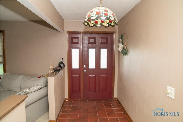 foyer entrance with dark tile patterned floors and baseboards