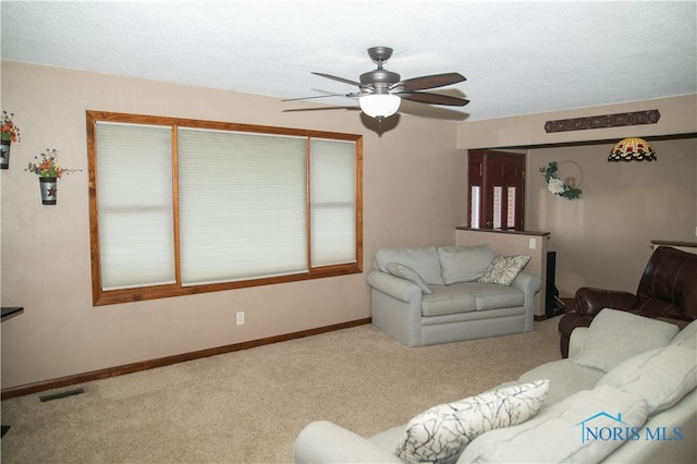 carpeted living room with ceiling fan and a textured ceiling