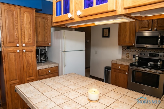 kitchen featuring stainless steel appliances, decorative backsplash, and tile counters