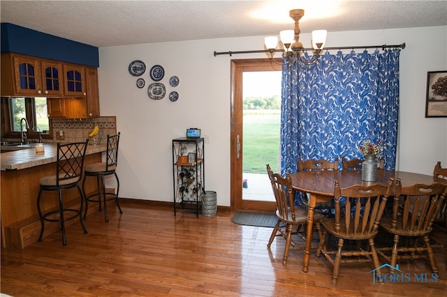 dining space featuring a textured ceiling, plenty of natural light, a chandelier, and hardwood / wood-style flooring