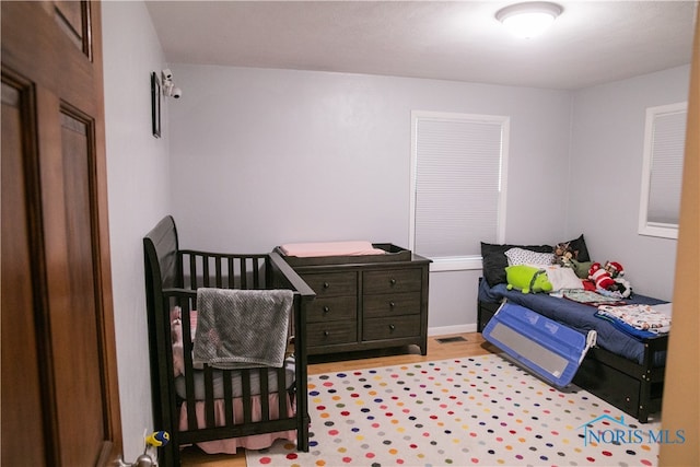 bedroom with a nursery area and light wood-type flooring