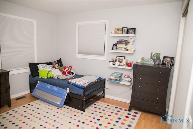 bedroom featuring wood finished floors, visible vents, and baseboards