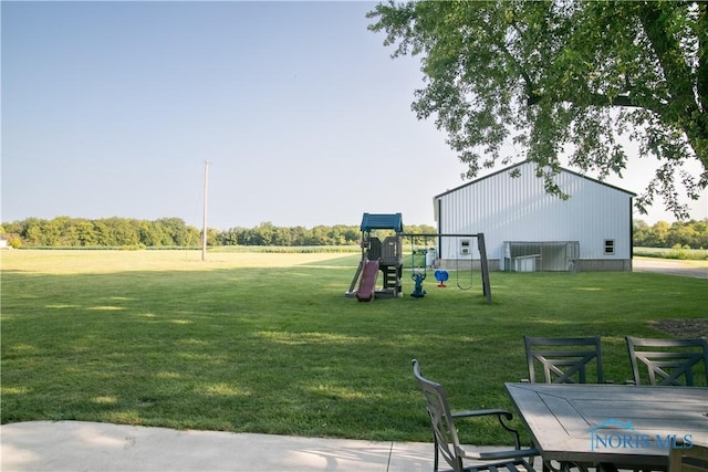 view of yard with an outbuilding, outdoor dining area, and playground community