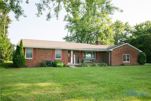 single story home with a chimney, a front lawn, and brick siding