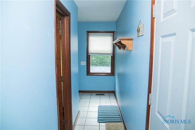 hallway featuring light tile patterned flooring, visible vents, and baseboards