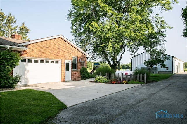 view of home's exterior with driveway, fence, and brick siding