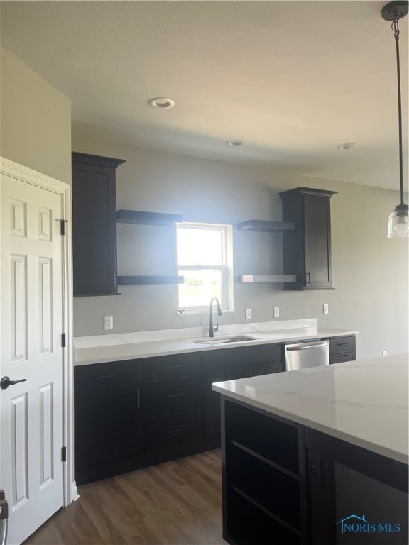 kitchen featuring dishwasher, decorative light fixtures, sink, light stone counters, and dark wood-type flooring