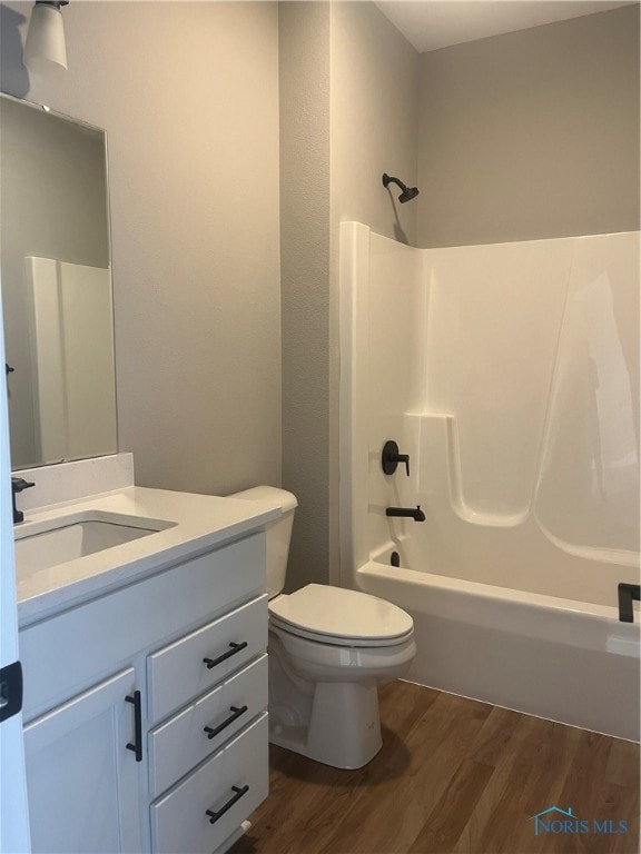 full bathroom with bathing tub / shower combination, hardwood / wood-style flooring, toilet, and vanity