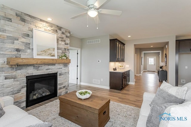 living room with light wood-style floors, visible vents, and ceiling fan
