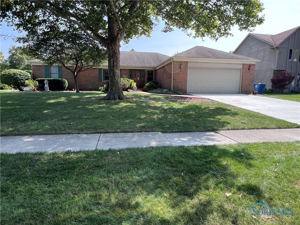 single story home featuring a garage and a front lawn