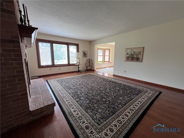 interior space with a textured ceiling, brick wall, wood-type flooring, and a fireplace