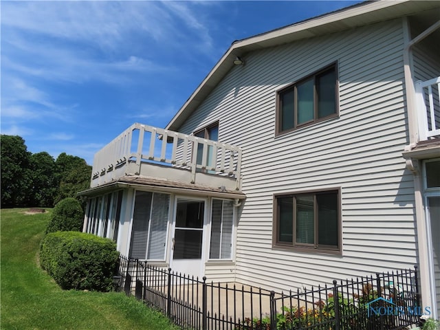 view of side of property featuring a balcony and a lawn