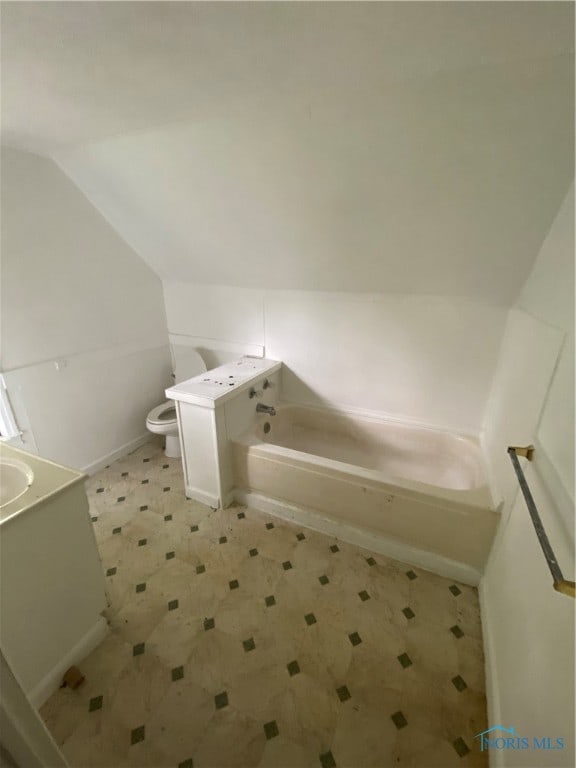 bathroom with toilet, vanity, tile patterned floors, a tub, and lofted ceiling